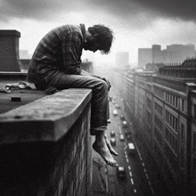 a black and white photo of a man sitting on the edge of a building overlooking a city