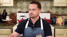 a man in an apron stands in front of a stove in a kitchen with a cookbook on the counter