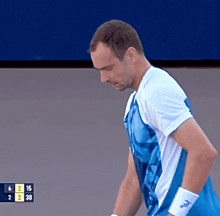 a man in a blue and white shirt is standing in front of a scoreboard that says 6 2 30