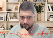 a man in front of a bookshelf with the words vou te mandar embora written below him