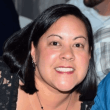 a woman is smiling for the camera and wearing a necklace .