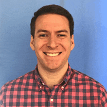 a man wearing a red and black plaid shirt is smiling