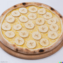 a pizza with banana slices on top is on a wooden board