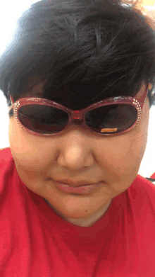 a woman wearing a red shirt and sunglasses has a yellow tag on the lens