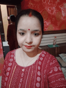 a woman with a red dot on her forehead smiles for the camera