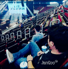 a man sits in a stadium with his feet up in front of a sign that says liam gallacher