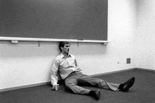 a man is sitting on the floor in a classroom with his legs crossed .