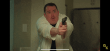 a man in a white robe is pointing a gun at the camera with gk written on the bottom right