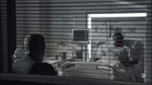 a man sits in a hospital room talking to a patient