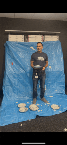 a man standing in front of a blue tarp holding two plates of food