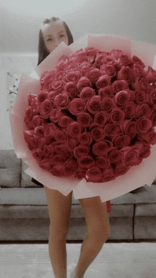 a woman holds a large bouquet of red roses