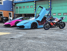 a pink sports car is parked next to a blue sports car and a red motorcycle