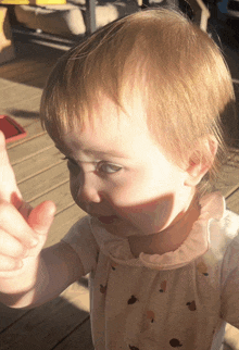 a little girl wearing a pink shirt with birds on it looks at something