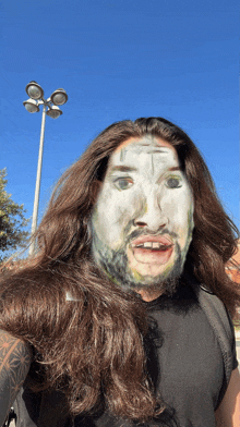 a man with long hair and a beard has his face painted white