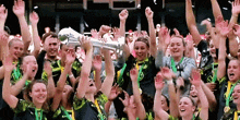 a group of people are celebrating with their arms in the air and a woman is holding a trophy with the letter w on it