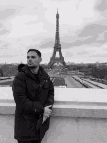 a black and white photo of a man standing in front of the eiffel tower