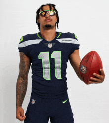 a man wearing a seahawks uniform holds a football