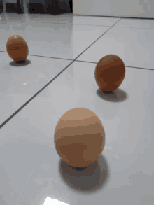 three eggs are sitting on a white tiled floor