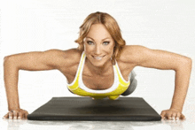 a woman in a yellow top is doing push ups on a mat