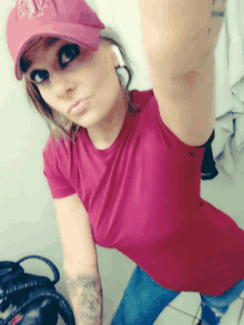 a woman taking a selfie wearing a red shirt and a baseball cap