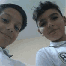 two young boys are taking a selfie together and smiling for the camera .