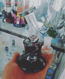 a person is holding a glass bong in their hand in front of a display case