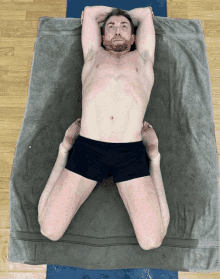 a shirtless man in black shorts is laying on a towel