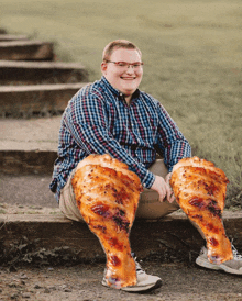 a man wearing glasses and a plaid shirt is sitting on a set of stairs with his legs wrapped in chicken