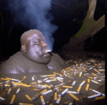 a man is smoking a cigarette while laying in a pile of cigarettes