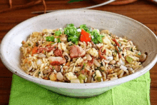 a bowl of rice with beans and meat on a green cloth