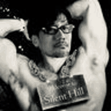 a black and white photo of a shirtless man wearing glasses and holding a book .