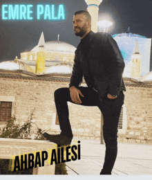 a man kneeling in front of a stone building with the name emre pala written above him