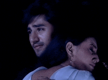 a man is holding a woman in his arms in a dark room