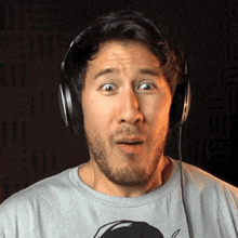 a man wearing headphones makes a surprised face while looking at the camera