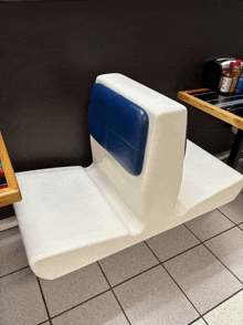 a white chair with a blue back rest sits next to a table