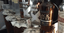 a bottle of absolut vodka is sitting on top of a pile of money on a table .