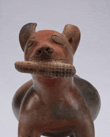 a statue of a dog with a snake in its mouth