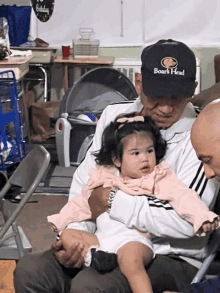 a man wearing a hat that says boark head holds a baby