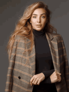 a woman in a black turtleneck and plaid jacket