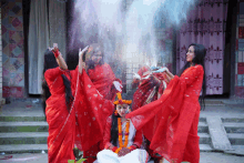 a group of women in red dresses are playing with powder