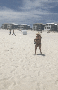 a woman in a bikini is holding a bottle of champagne on a beach