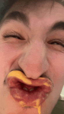 a man is making a funny face with a piece of pizza in his mouth .