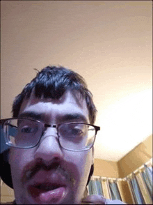 a man with glasses and a mustache is licking his lips .