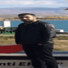 a man in a black jacket stands in front of a sign that says ' enti er '