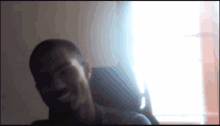 a blurry picture of a man in a chair with a window in the background