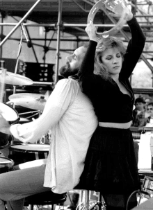 a woman is holding a tambourine while a man plays the drums