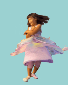 a little girl in a purple dress and pink shoes is dancing