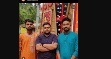 three men are posing for a picture with their arms crossed in front of a bamboo wall