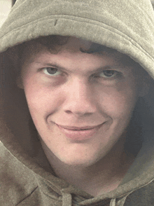 a young man wearing a hooded sweatshirt is smiling for the camera