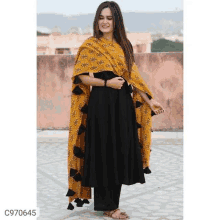 a woman wearing a black dress with a yellow dupatta .